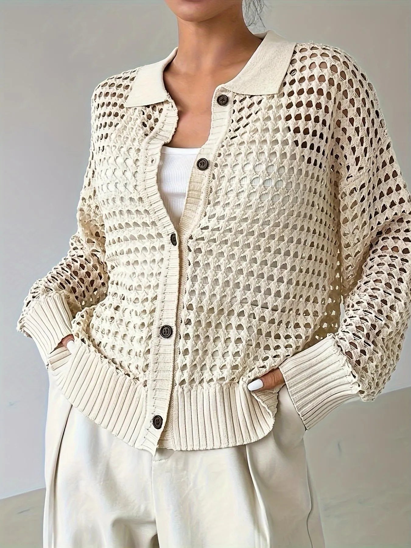 Beige knitted cardigan worn by a person on a plain background
