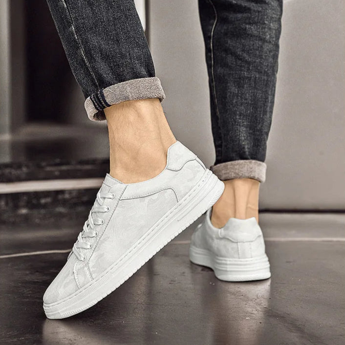 White sneakers worn with dark jeans on a neutral background