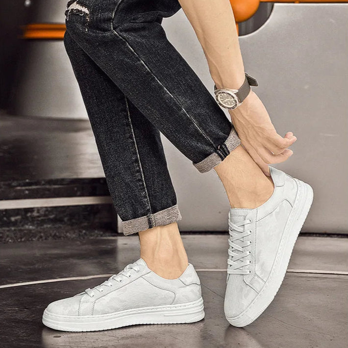 White sneakers worn with black jeans on a blurred background