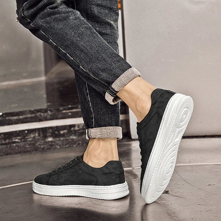 Person wearing black sneakers with white soles on a neutral background