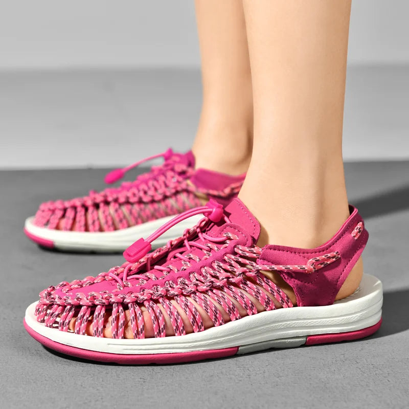 Pink sandals with white soles worn by a person on a gray background