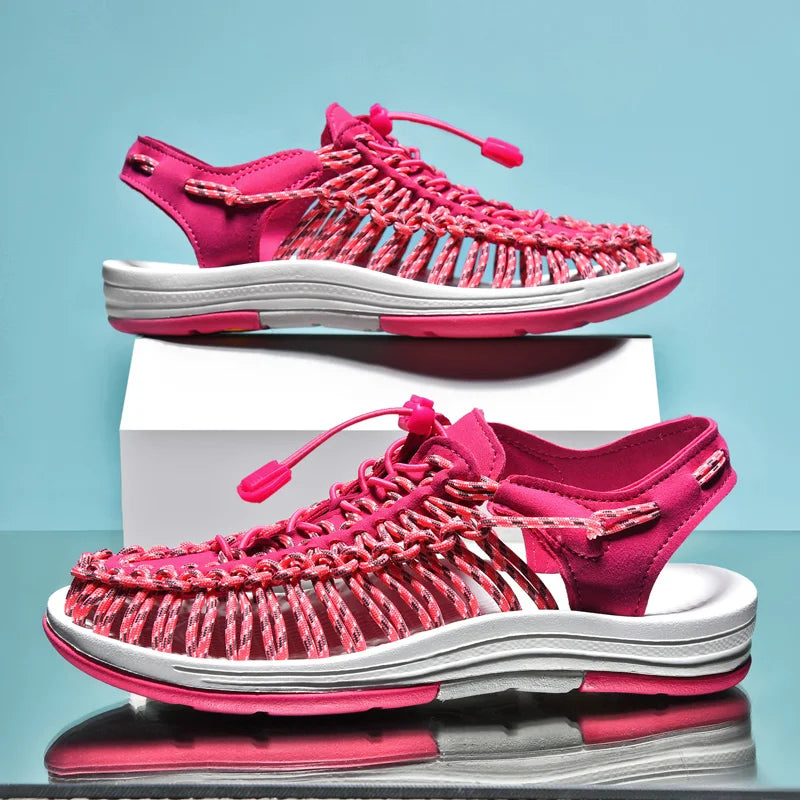 Pink sandals with white soles on a reflective surface and light blue background