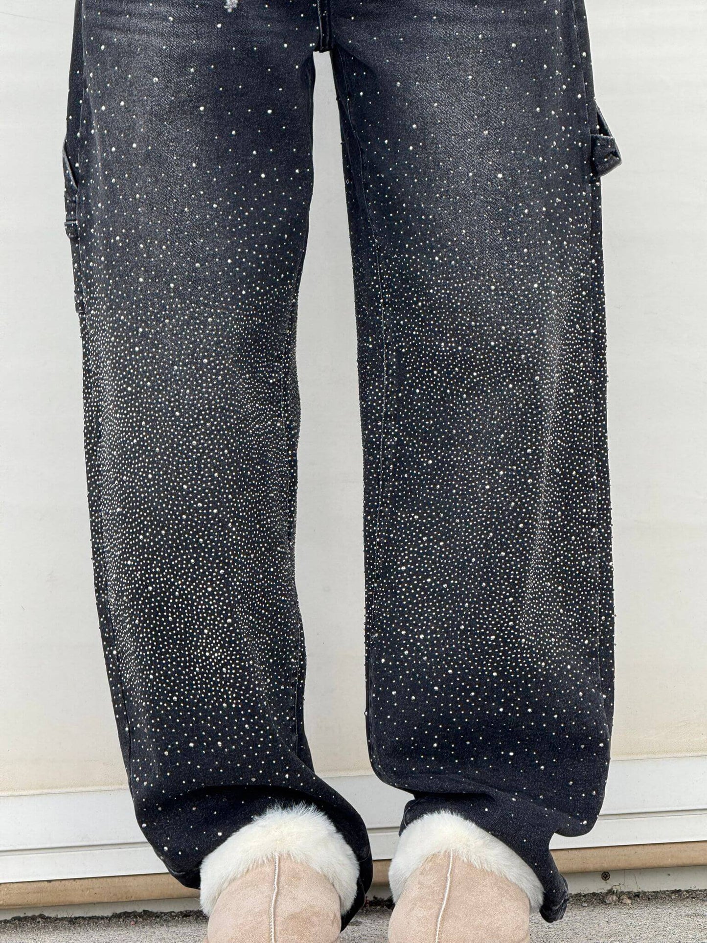 Black pants with white speckles worn by a person, standing on a white floor.