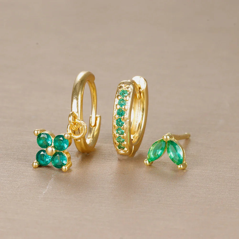 Gold earrings with green gemstones on a beige background