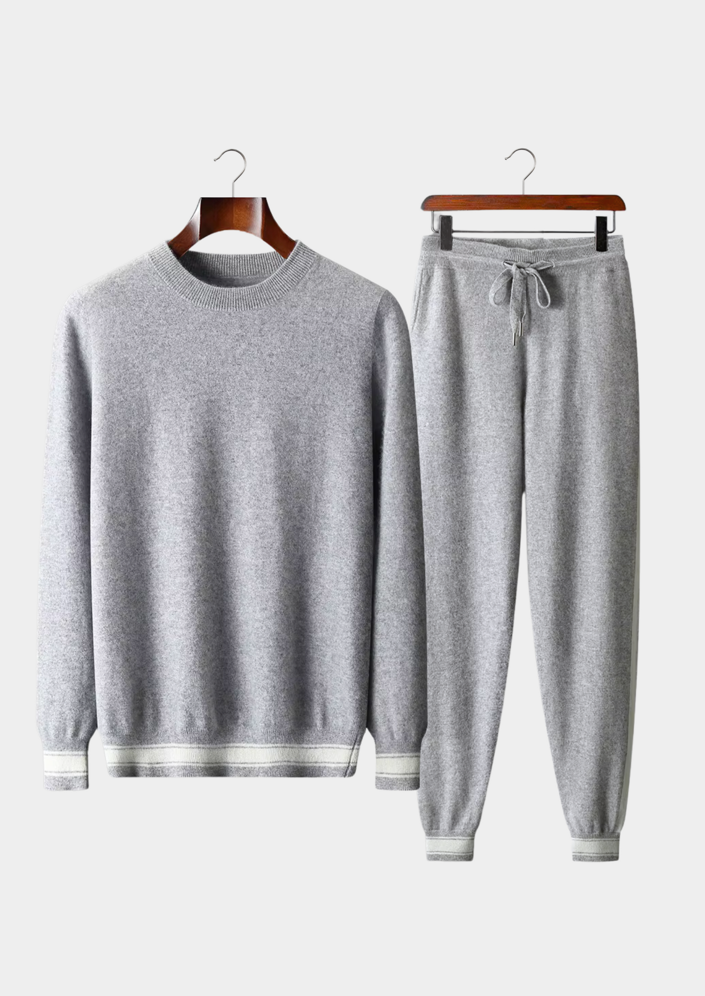 Gray sweater and pants set on hangers against a white background