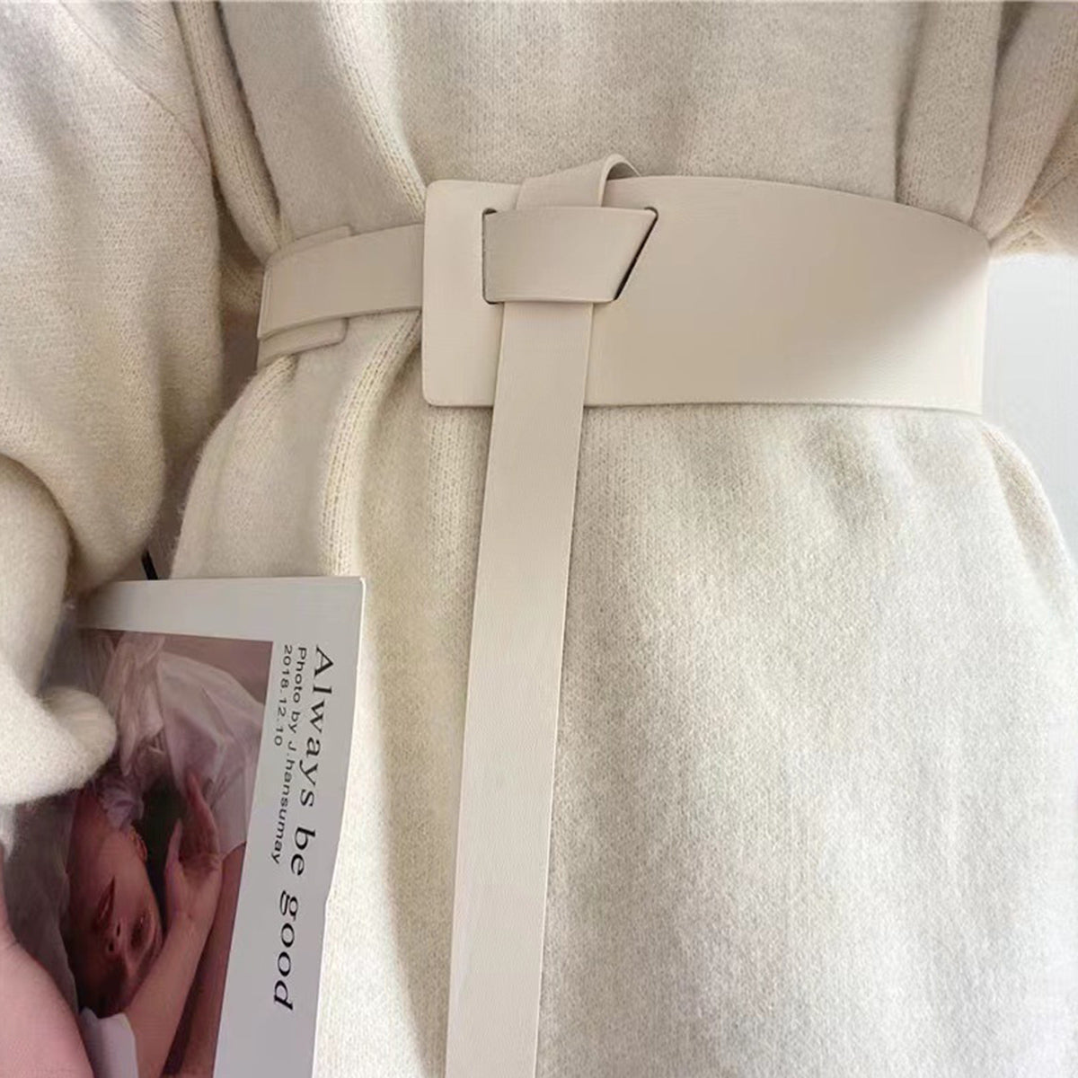 Close-up of a person wearing a beige coat holding a book titled 'Always be good'.