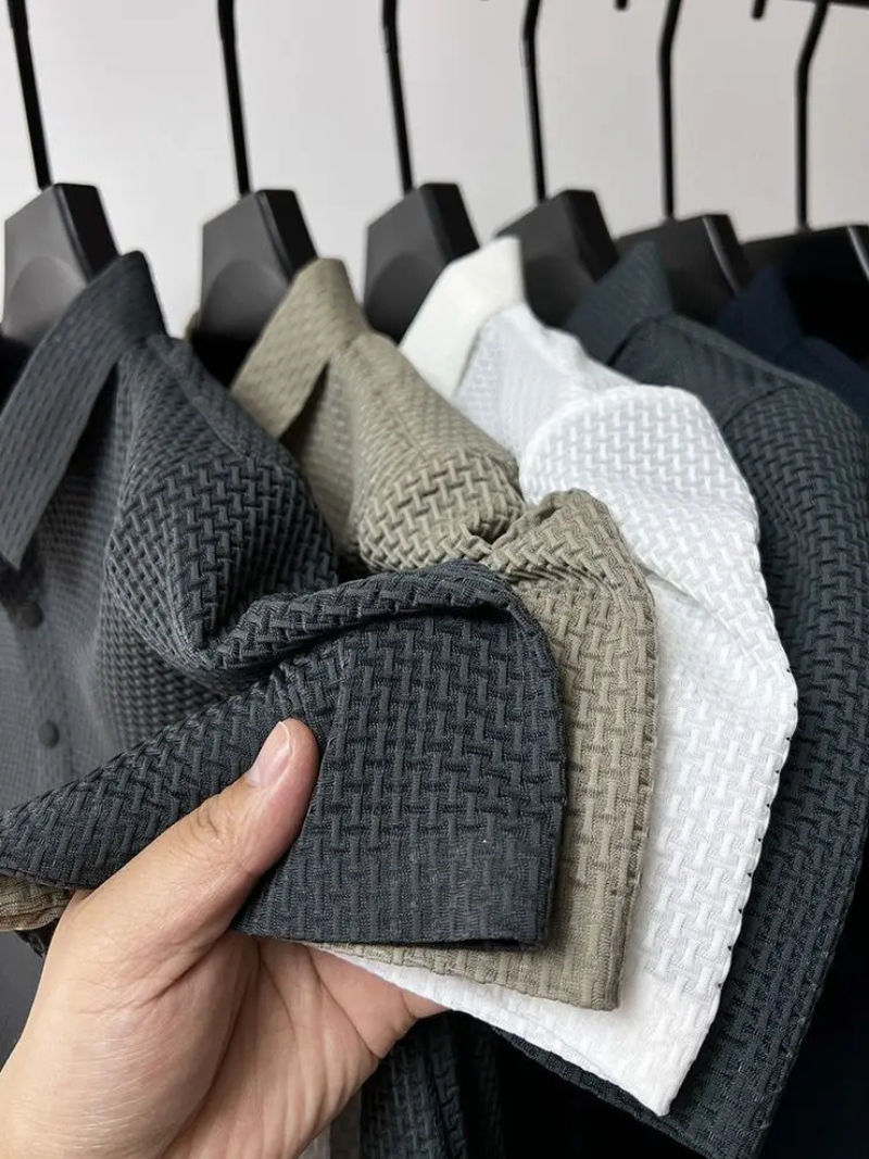 Hand holding a textured fabric swatch against a rack of other fabric samples.
