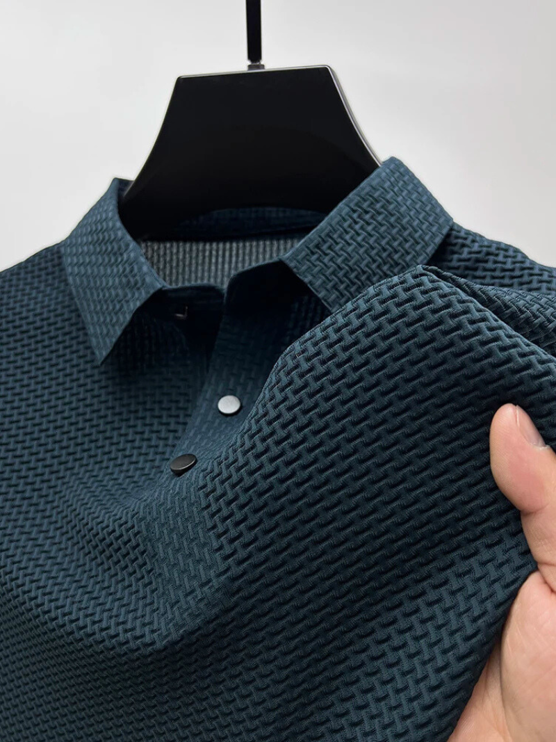 Teal textured polo shirt on a hanger with a hand touching the fabric.