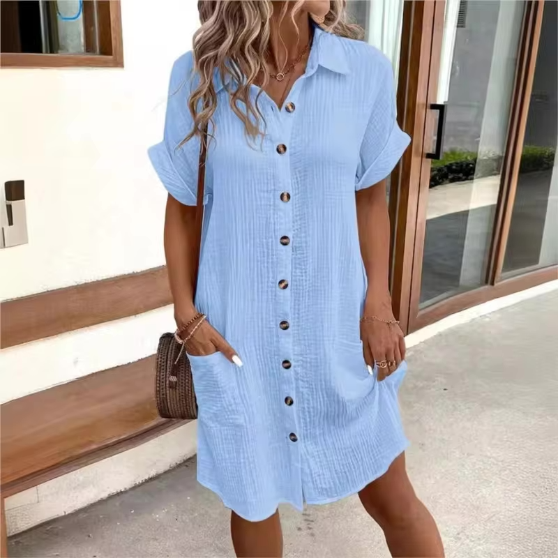 Woman wearing a light blue dress with buttons outdoors.