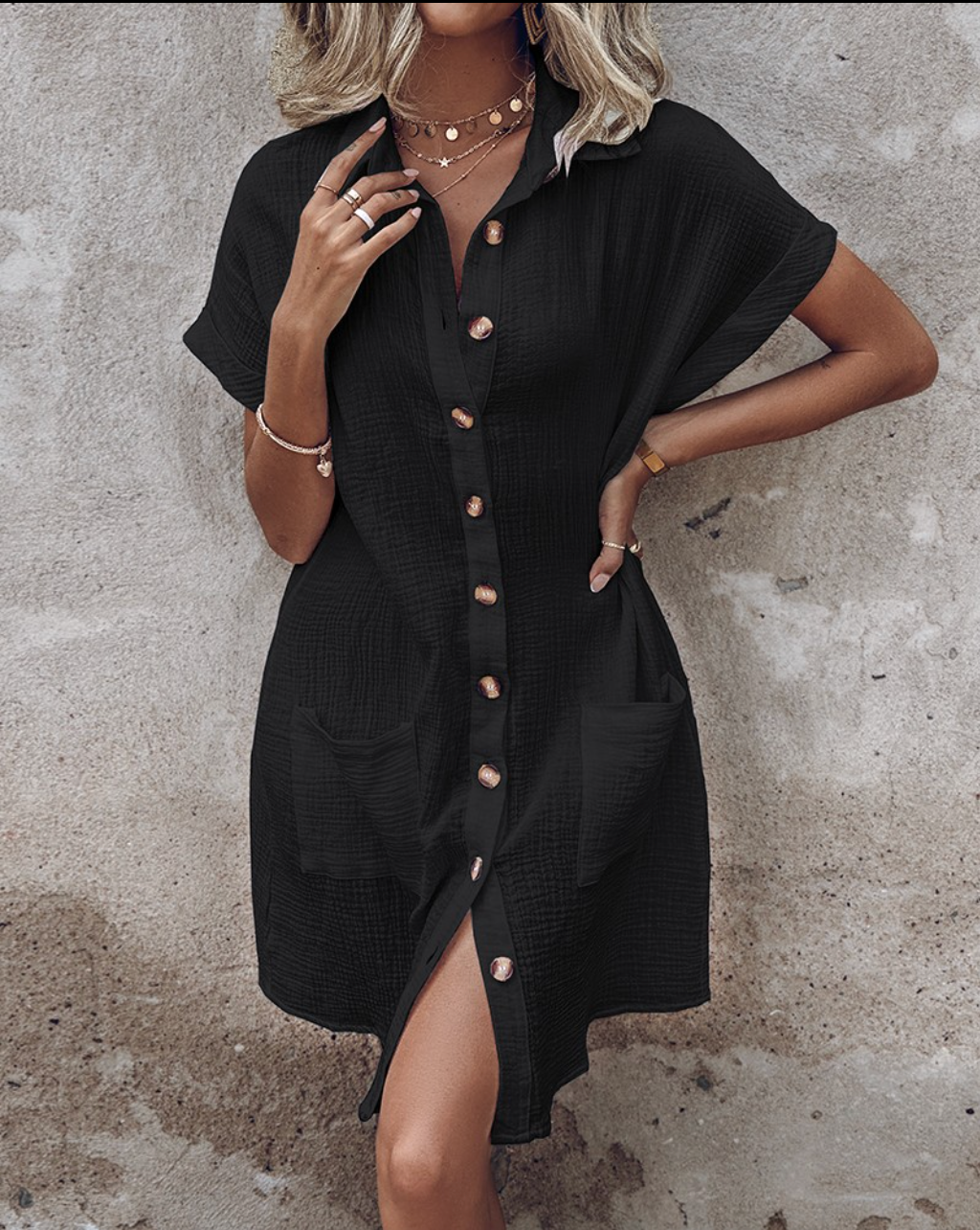 Woman wearing a black dress with a textured pattern against a textured wall.
