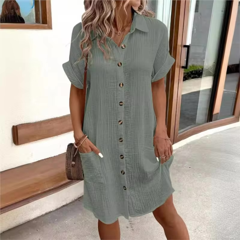 Woman wearing a green button-up dress standing outdoors.