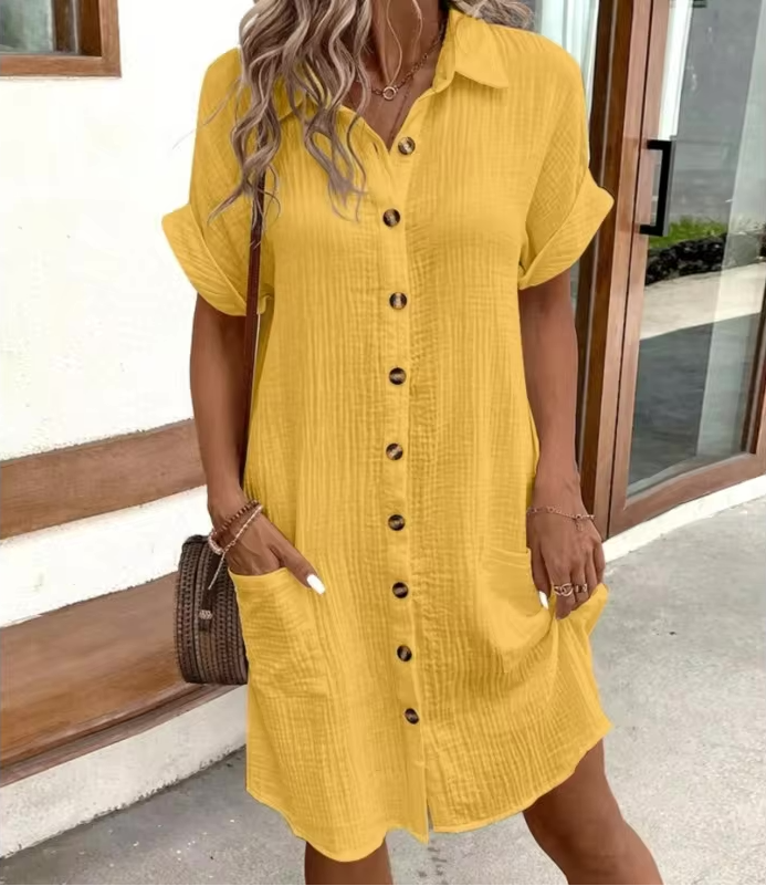 Woman wearing a yellow dress with buttons, standing outdoors.