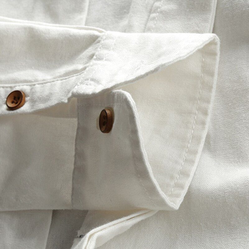 Close-up of a white denim shirt with rolled-up sleeves and brown buttons.