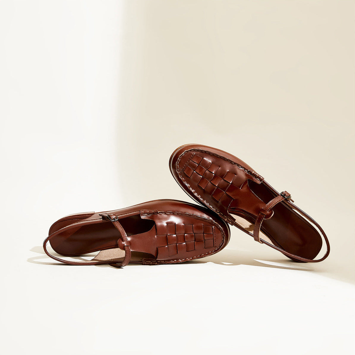 Pair of brown leather sandals on a beige background