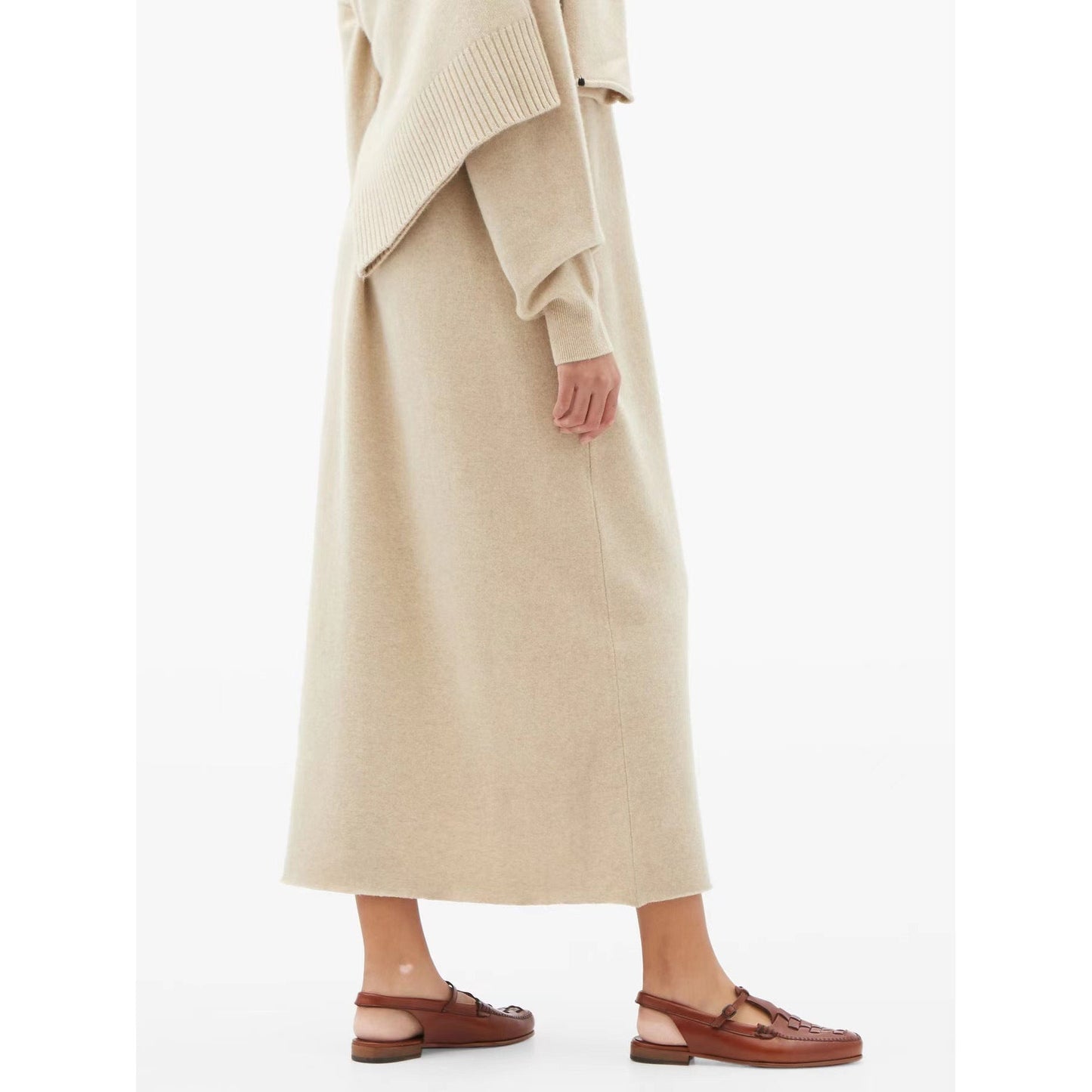 Person wearing a long beige coat and brown sandals on a white background
