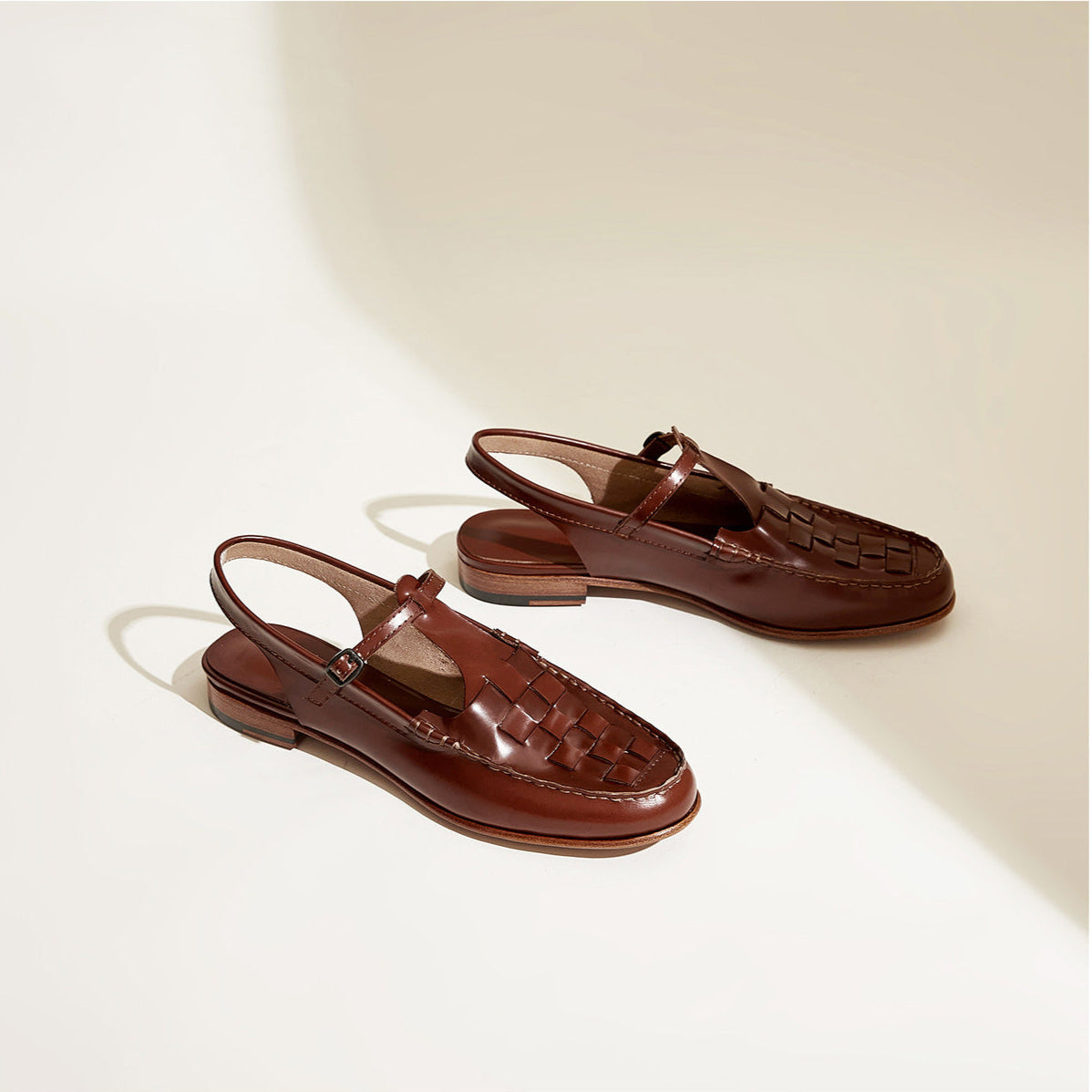 Pair of brown leather sandals on a light beige background