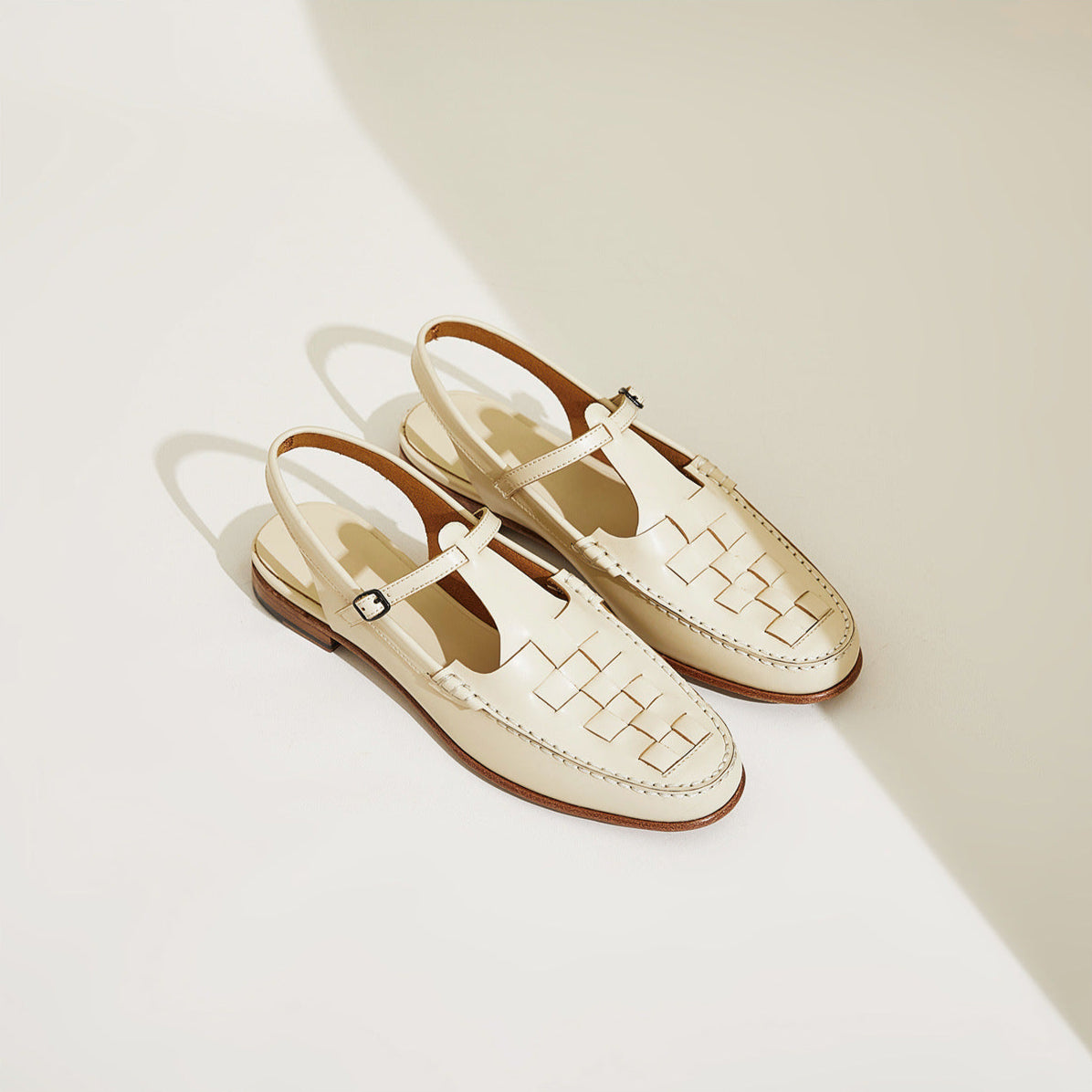 Pair of cream-colored sandals with woven pattern on a light background