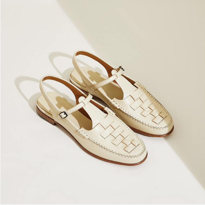 Pair of cream-colored loafers with woven design on a light background