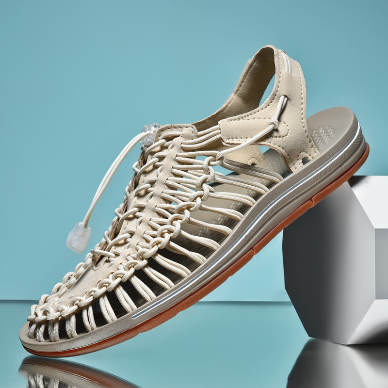 Beige sandal with braided design on a reflective surface with a blue gradient background