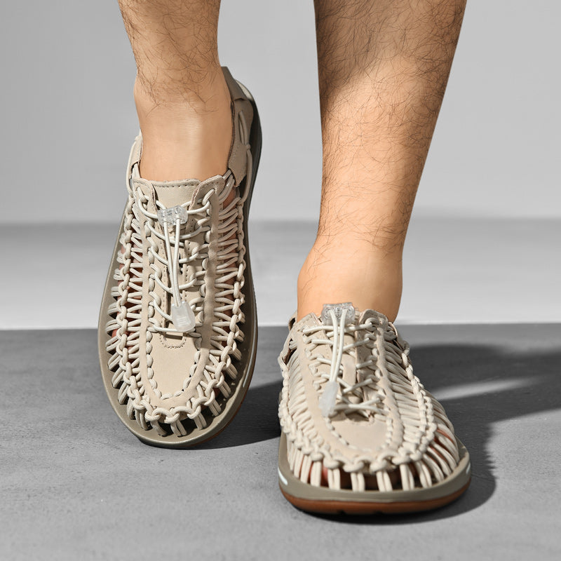 Beige woven sandals worn by a person on a gray background