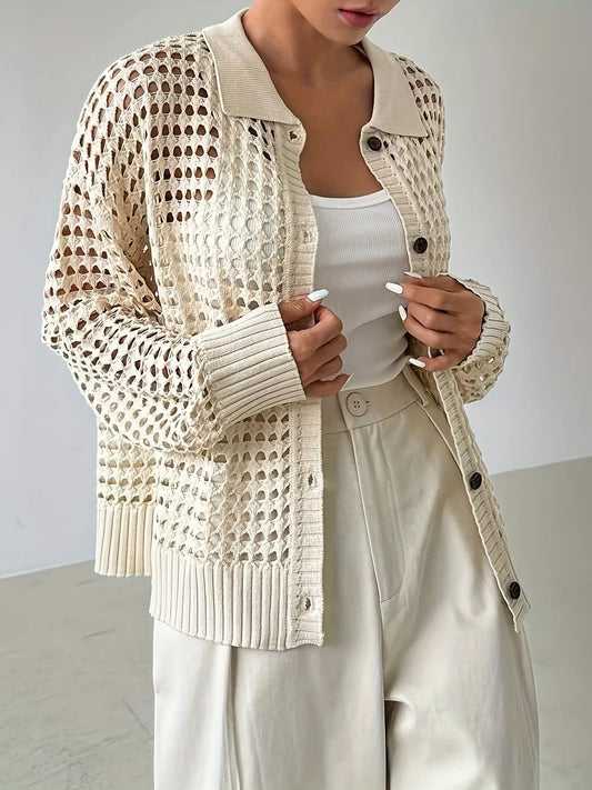 Person wearing a beige knitted cardigan with black buttons on a plain background
