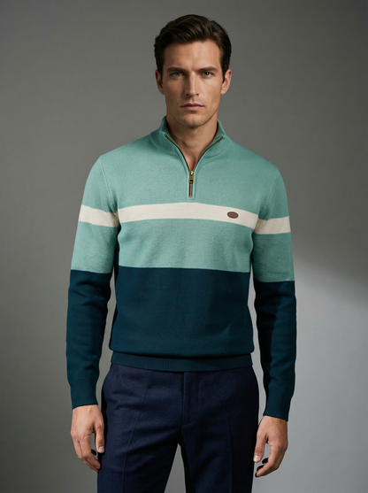 Man wearing a teal and navy sweater with a white stripe on a gray background