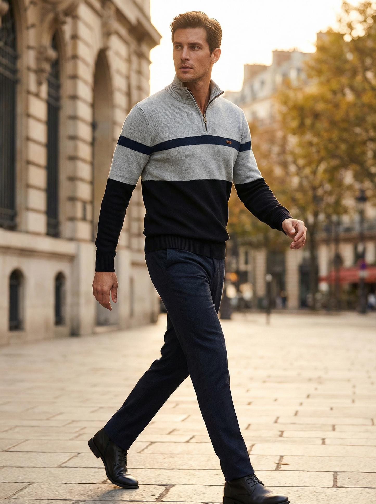 Man walking on a city street wearing a gray and black sweater with a zipper.