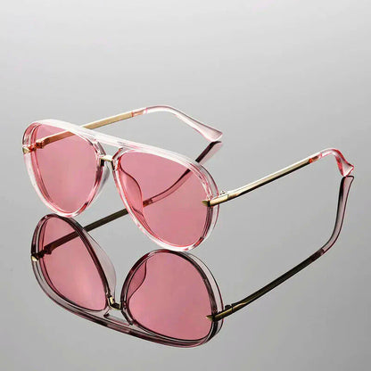 Pink sunglasses with gold frames on a gray background