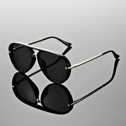 Black sunglasses with gold frames on a reflective gray surface