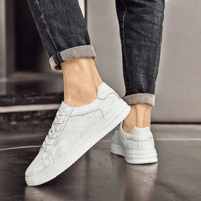 White sneakers worn with dark jeans on a neutral background