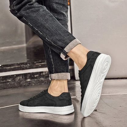 Person wearing black sneakers with white soles on a neutral background
