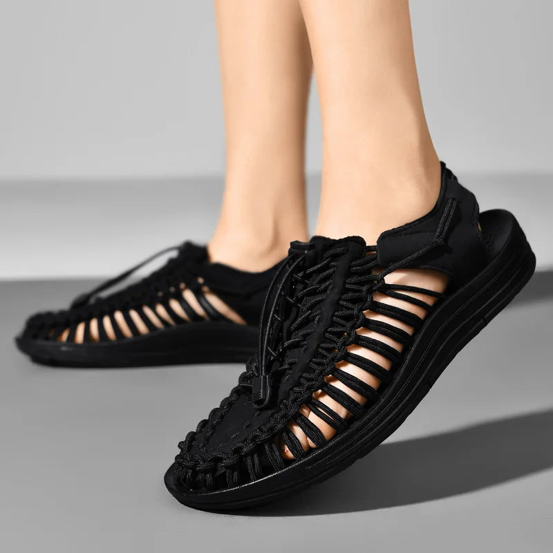 Black sandals with open-toe design worn by a person on a gray background