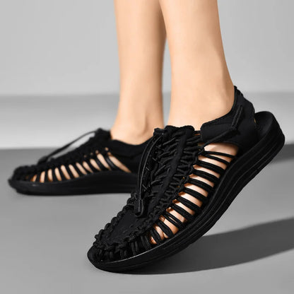Black sandals with open-toe design worn by a person on a gray background
