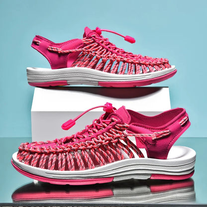 Pink sandals with white soles on a reflective surface and light blue background