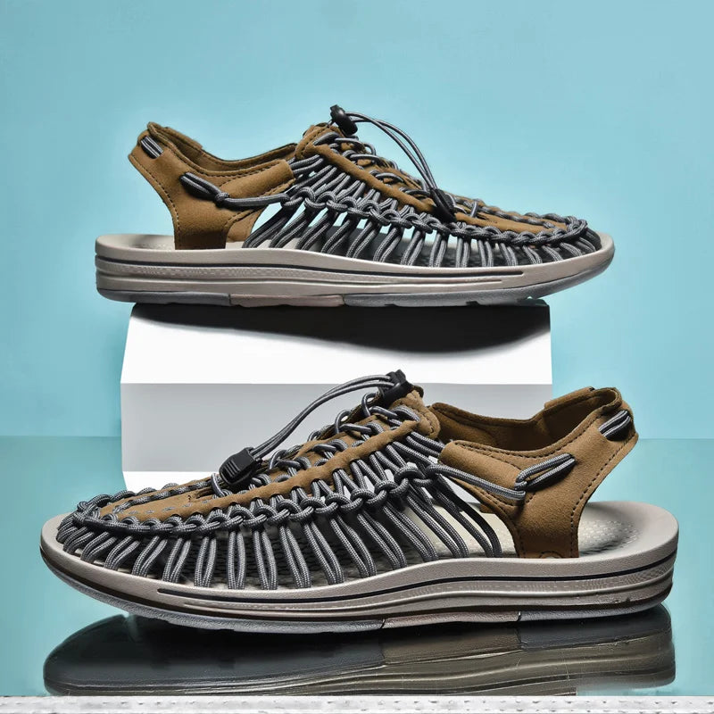 Pair of brown and gray sandals on a reflective surface with a light blue background