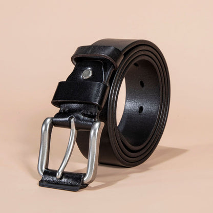 Black leather belt with silver buckle on a beige background