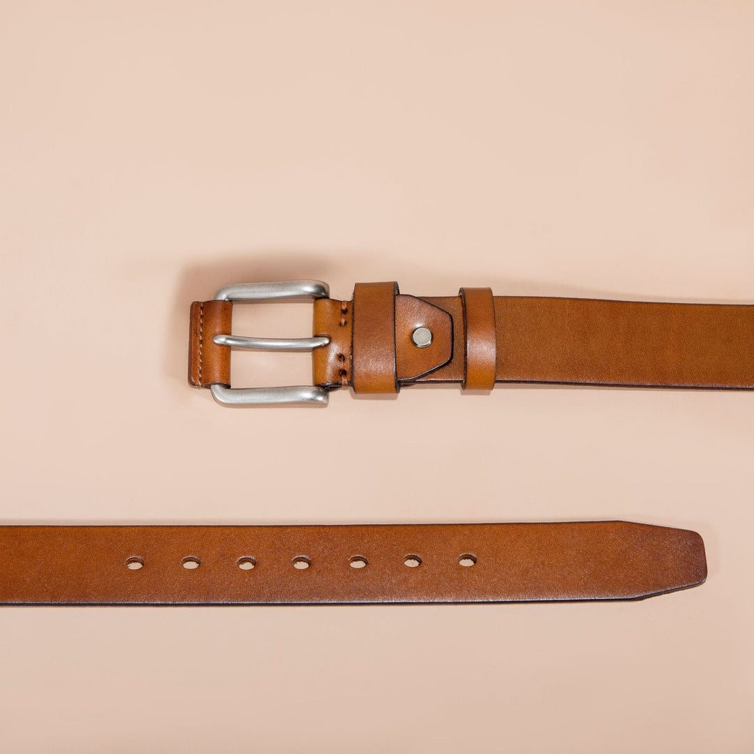 Brown leather belt with silver buckle on a beige background