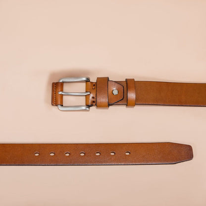 Brown leather belt with silver buckle on a beige background