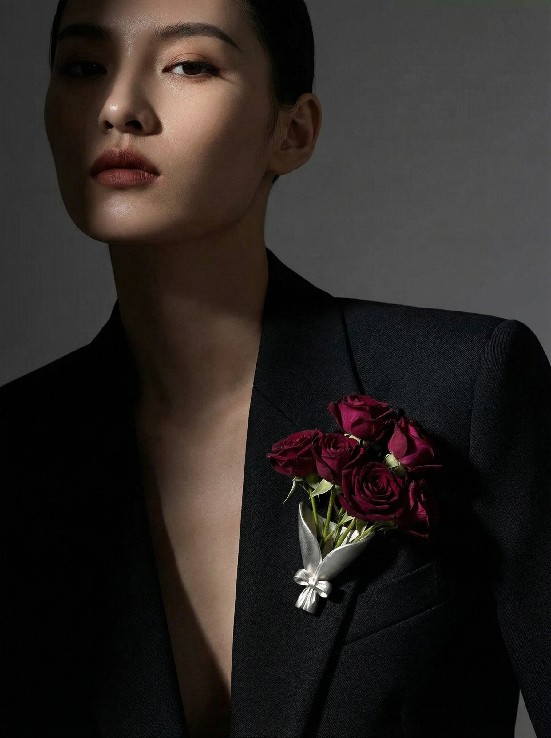 Person wearing a black suit with red roses on a dark background