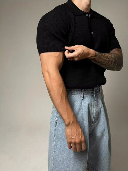 Person wearing a black polo shirt and light blue jeans against a neutral background