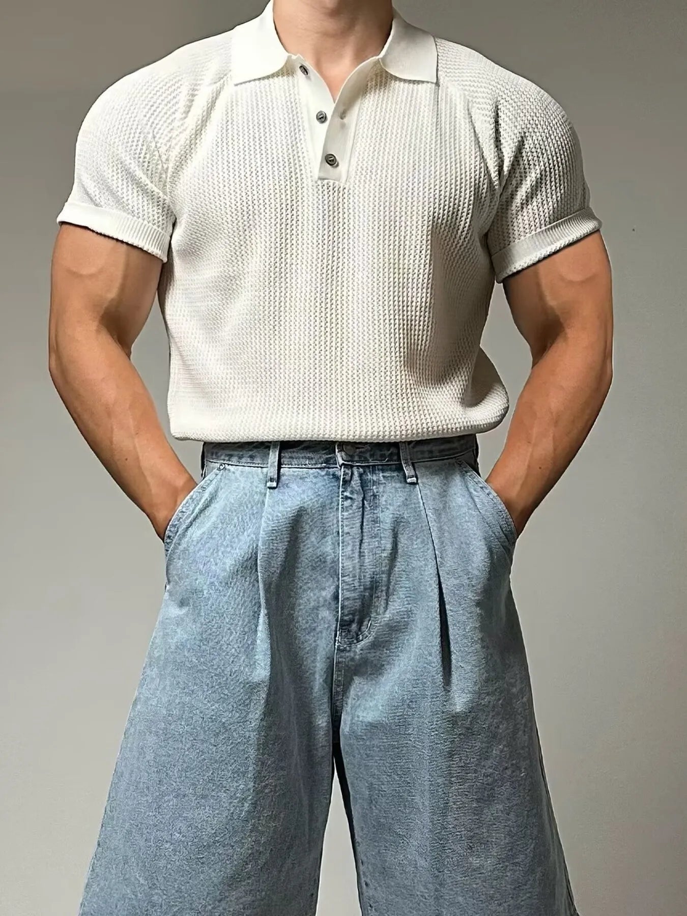 Person wearing a textured white polo shirt and light blue pants on a gray background