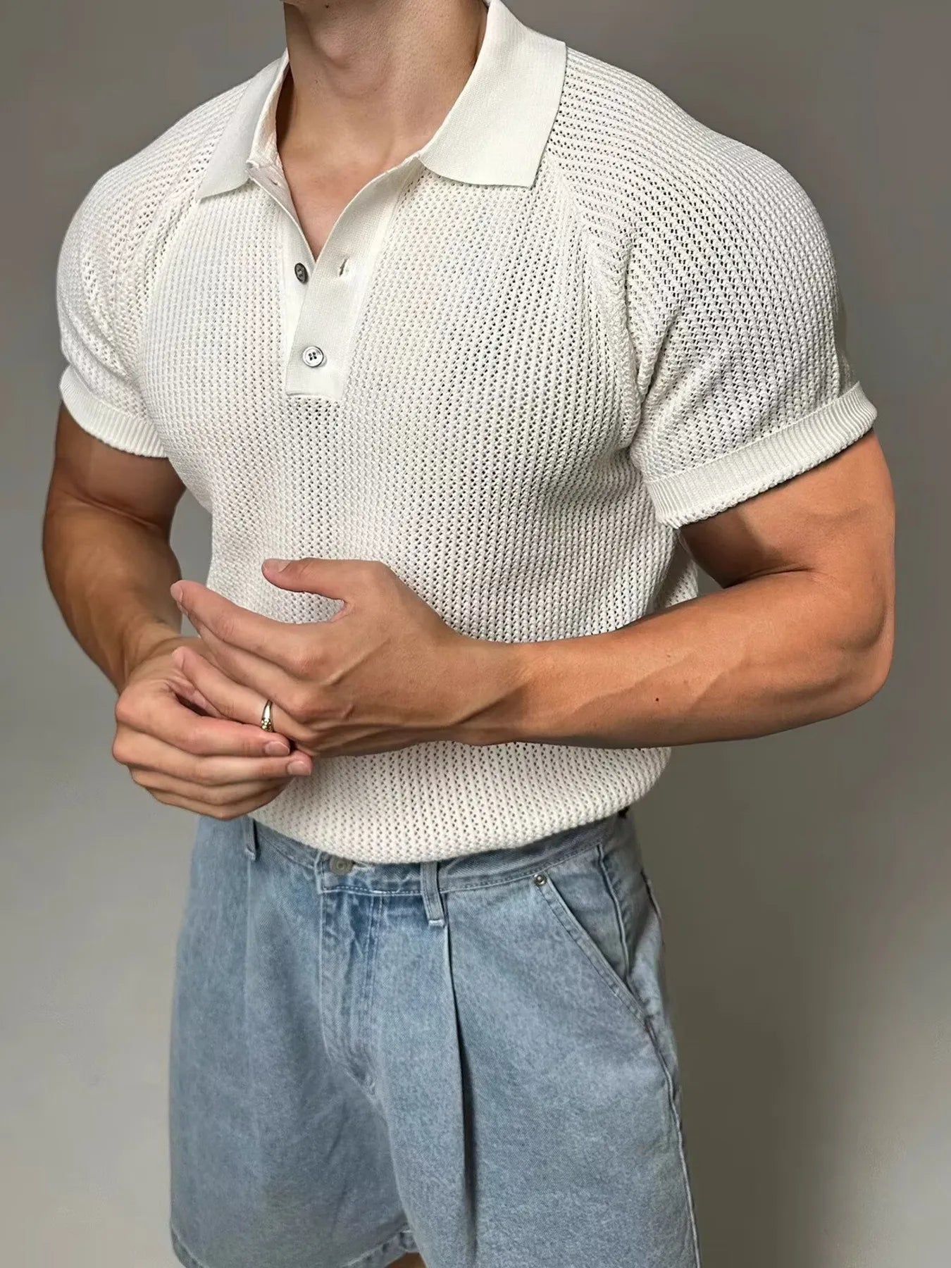 Person wearing a textured white polo shirt and light blue jeans against a gray background