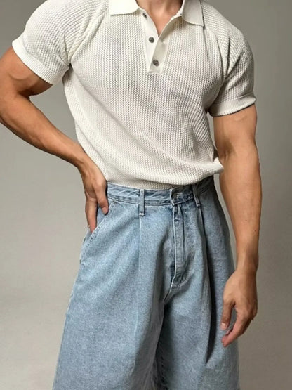 Person wearing a textured white polo shirt and light blue jeans against a neutral background