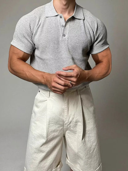 Man wearing a textured short-sleeve shirt and light-colored pants against a plain background