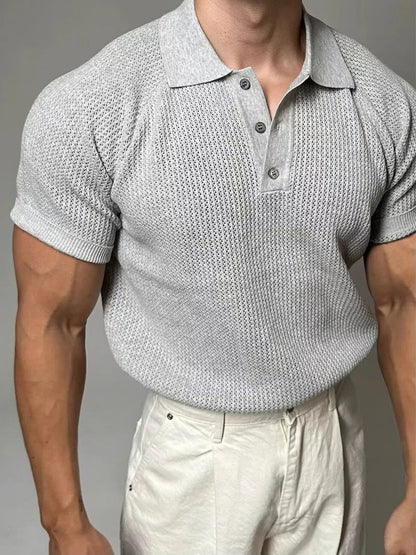 Man wearing a textured gray short-sleeve shirt and light-colored pants against a neutral background
