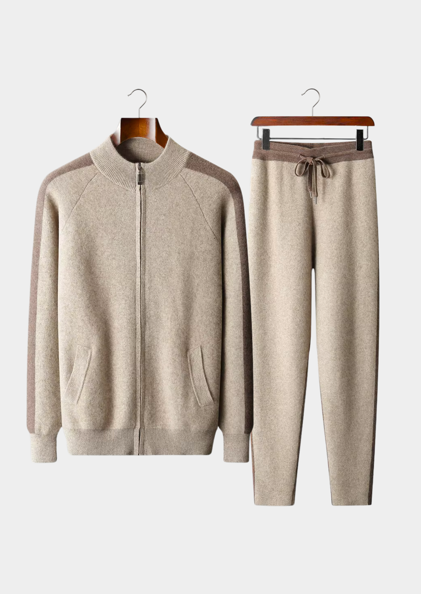 Beige tracksuit with a jacket and pants on hangers against a white background