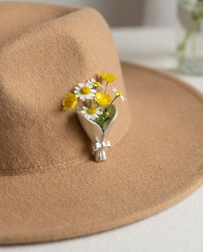 Brown hat with a decorative flower brooch featuring yellow and white flowers.