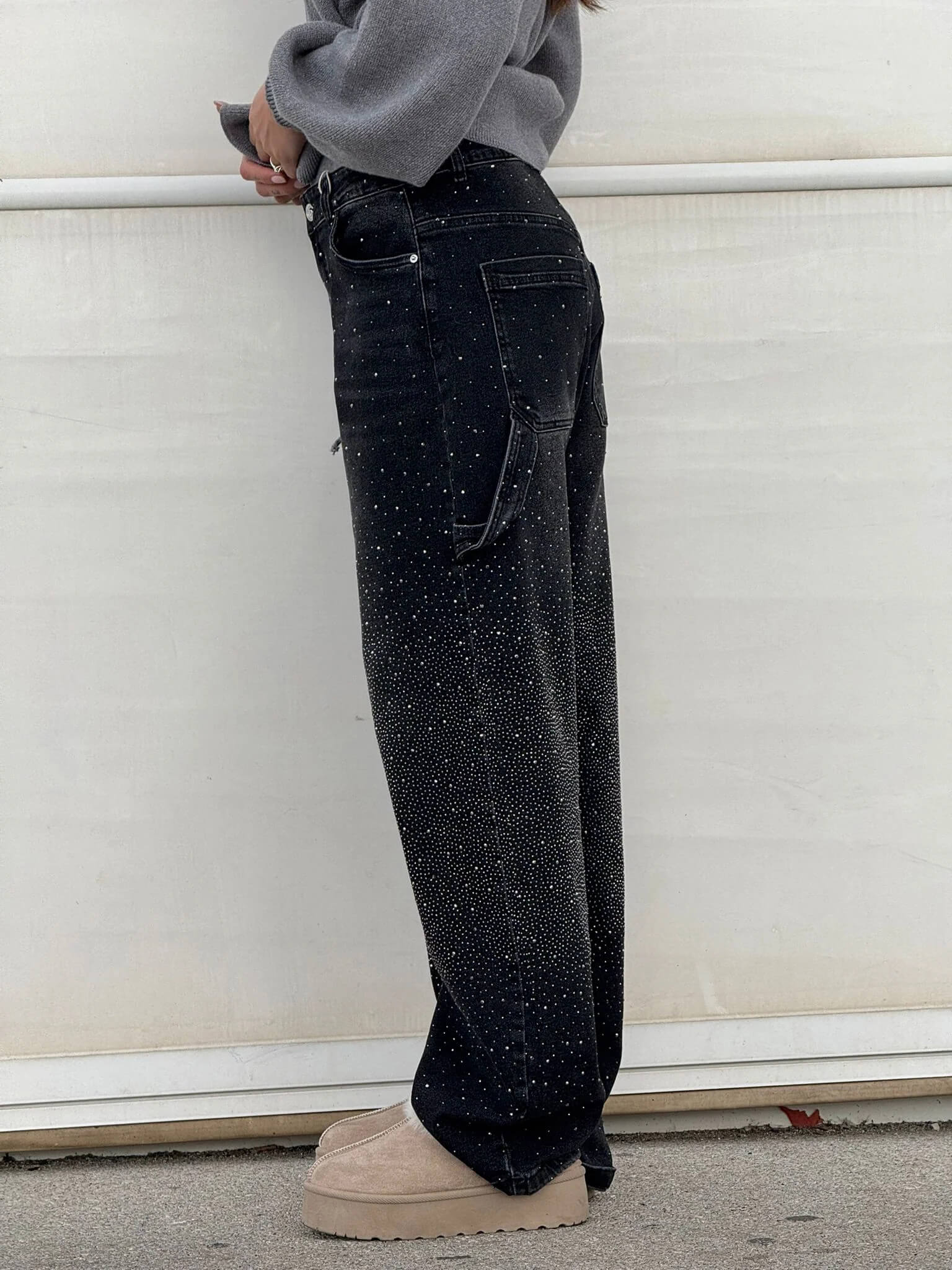 Person wearing black jeans with white speckles against a white background