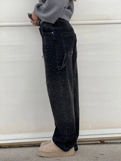 Person wearing black jeans with white speckles against a white background