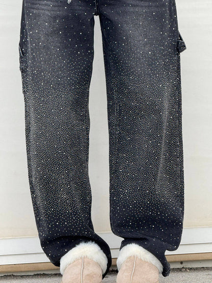 Black pants with white speckles worn by a person, standing on a white floor.